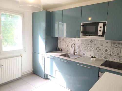 une cuisine avec des armoires bleues, un évier et une fenêtre dans l'établissement Family-friendly First-class Appartment, Évry-Courcouronnes