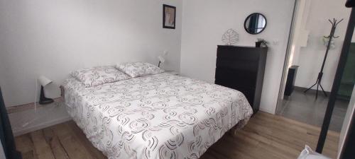 a bedroom with a white bed and a black dresser at Maison de bord de mer - proche plage in La Turballe