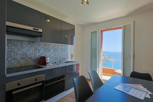 une cuisine avec une table et une vue sur l'océan dans l'établissement Apartment Lucioles - Strandnah mit Balkon und Meerblick by Riviera HomeLife, à Anthéor