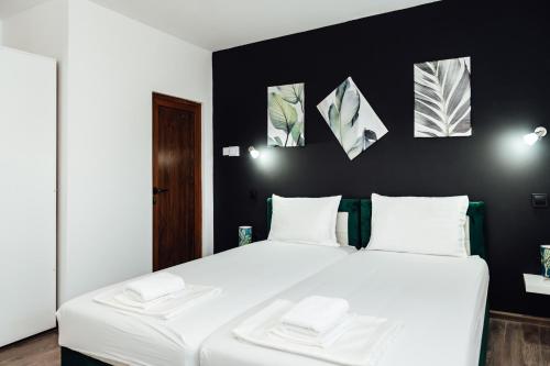 a bedroom with a large white bed with black walls at Къщи за гости БРИК in Sapareva Banya