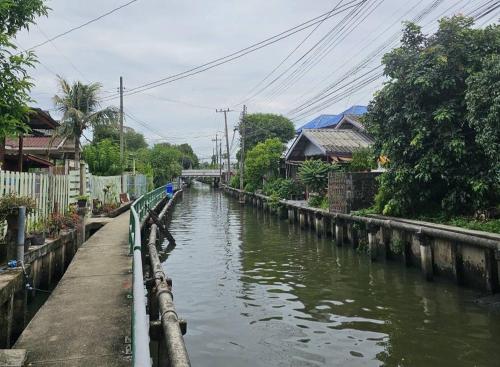 a canal of water with houses on the side at Nipatra Homestay in Ban Khlong Bang Sai