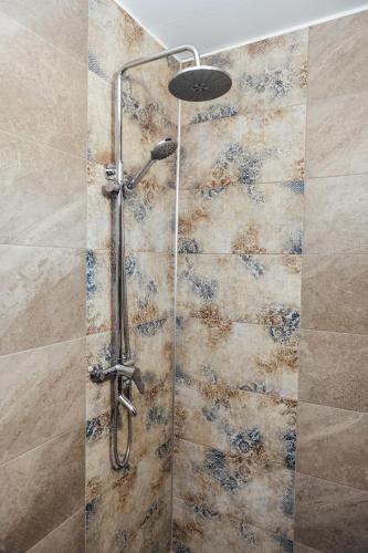 a shower in a bathroom with a stone wall at Къщи за гости БРИК in Sapareva Banya