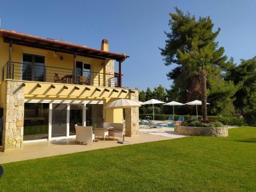 a house with a patio and a pool with umbrellas at Villa Palatina in Paliouri