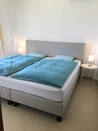a bedroom with a bed with blue sheets and a table at Villa Palatina in Paliouri