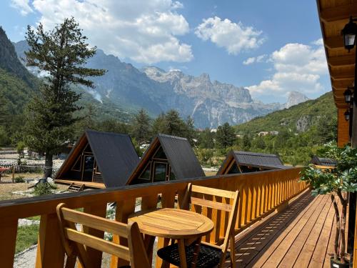 a wooden deck with a table and chairs and mountains at Thethi Villas in Theth