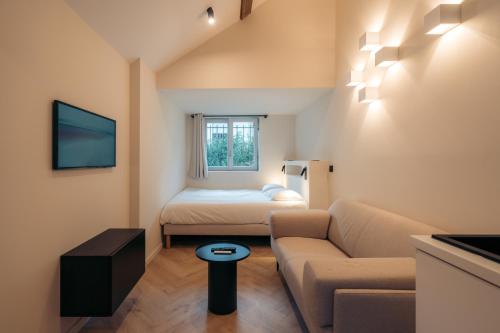 - un petit salon avec un canapé et un lit dans l'établissement La Salamandre, à Fontainebleau