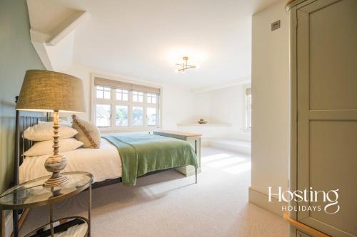 ein Schlafzimmer mit einem Bett und einem Tisch mit einer Lampe in der Unterkunft Dragon Court - 4 Beds with Terrace Garden in Henley on Thames