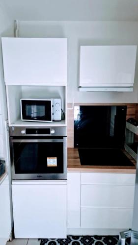 Il comprend une cuisine blanche équipée d'un four micro-ondes et d'une cuisinière. dans l'établissement Votre maison loin de chez Vous !, à Chanteloup-les-Vignes