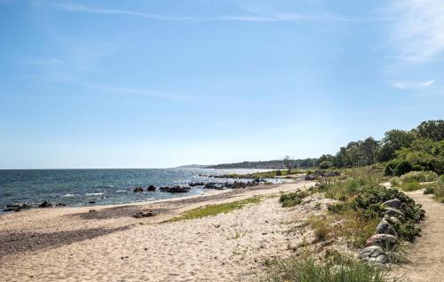 a sandy beach next to the ocean on a sunny day at Cozy Apartment In Allinge With Wifi in Allinge