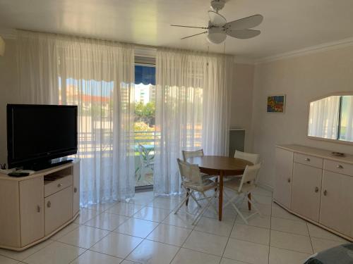 un salon avec une table à manger et une télévision dans l'établissement T2 à proximité des plages, à Cannes