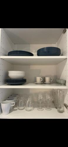 une étagère blanche avec des assiettes, des bols et de la vaisselle dans l'établissement Suite moderne au cœur du 8e, à Paris