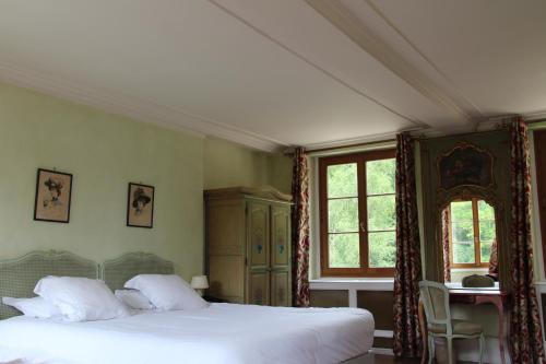 a bedroom with a bed and a table and windows at Hostellerie Du Château Les Muids in La Ferté-Saint-Aubin