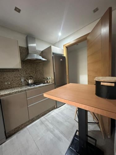 a kitchen with a wooden table and a refrigerator at Rock Island Appartement Haut standing pied dans l'eau Mohammedia in Mohammedia