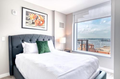 Un dormitorio con una cama y una ventana grande. en Luxury Apt with Balcony In Seaport, en Boston