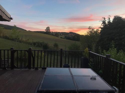 a table on a deck with a sunset in the background at 5f Stanley Lodge, Caer Beris, Builth Wells - No tradesman in Builth Wells