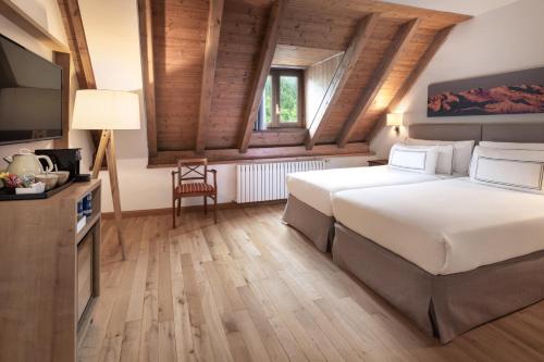 a bedroom with a large white bed and a television at Meliá de Tredós in Tredós