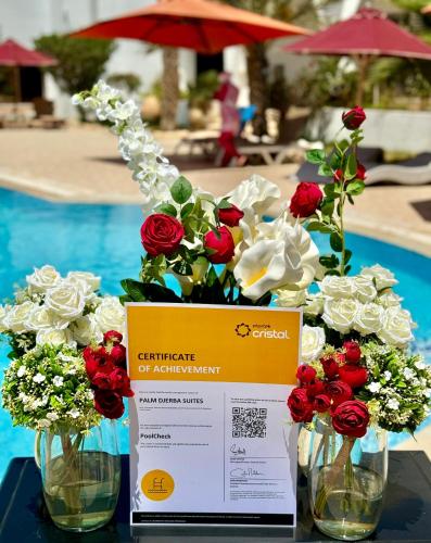 a table with two vases filled with red and white flowers at Palm Djerba Suites in Mezraya