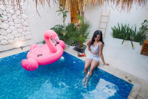 a woman sitting next to a pink flamingo in a swimming pool at Dupadi Villa Jogja With Privatepool in Jetis