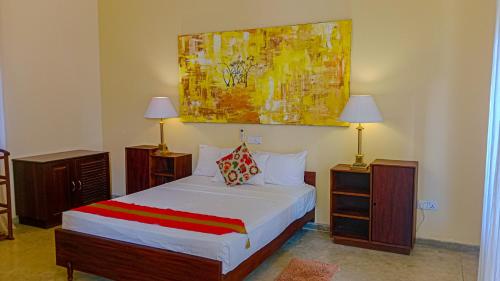 a bedroom with a bed with two lamps and a painting at Sigiri Lanka Resort in Sigiriya