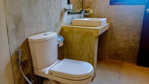 a bathroom with a white toilet and a sink at Sigiri Lanka Resort in Sigiriya