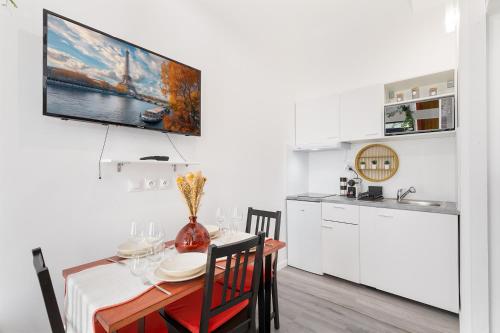 Il comprend une cuisine et une salle à manger avec une table et une télévision. dans l'établissement Confort et élégance à Paris 17, à Paris