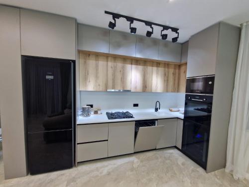 a kitchen with wooden cabinets and a black refrigerator at Villa-Riverside in Ch'aisubani