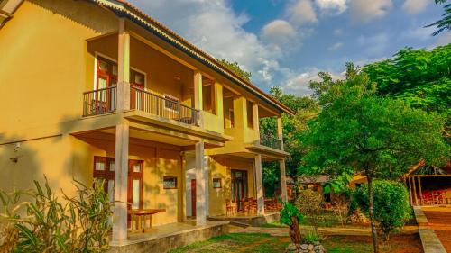 a yellow house with a balcony and a yard at Sigiri Lanka Resort in Sigiriya