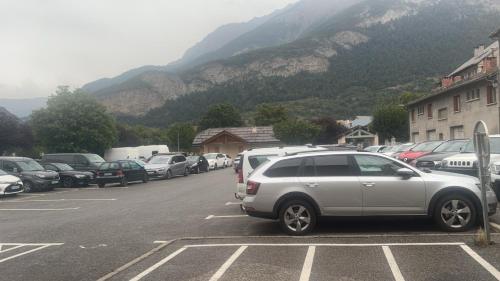 - un parking avec des voitures garées devant une montagne dans l'établissement Studio bien équipé, à Jausiers
