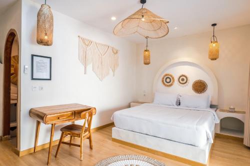 a bedroom with a white bed and a wooden table at Dupadi Villa Jogja With Privatepool in Jetis