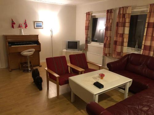 a living room with a couch and a table and a piano at Andsnes Velhus in Loppa