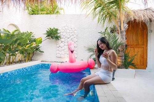 a woman in a white dress sitting next to a swimming pool at Dupadi Villa Jogja With Privatepool in Jetis