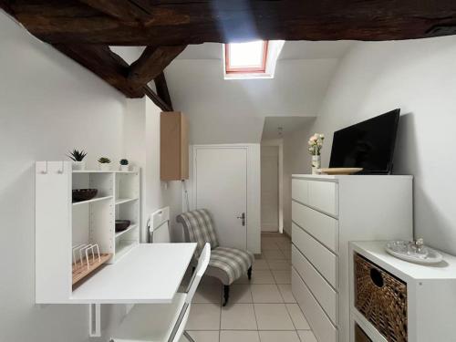 - une cuisine blanche avec une table et une chaise dans l'établissement Le Tiny- Parking gratuit- Boulangerie, à Sens