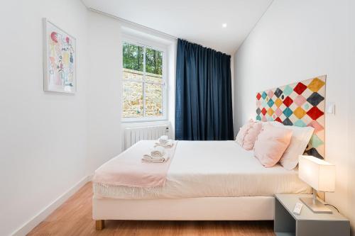 a bedroom with a large white bed with a window at GuestReady - Serene Hideout in Downtown in Porto
