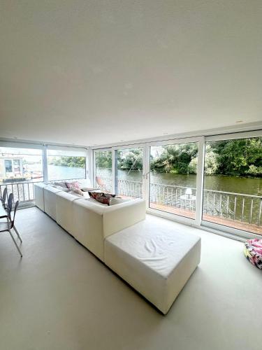 a large living room with a white couch and windows at Houseboat PURE II in Vreeland