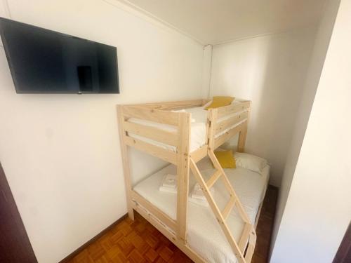 a room with a bunk bed and a television on a wall at Gerês Guest House in Geres