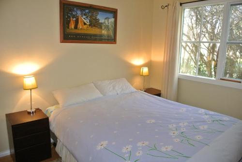 a bedroom with a bed and two lamps and a window at Corinda Cottage - 4 bedroom pet friendly in Bright