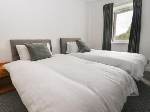 two white beds in a room with a window at Campion Cottage in Watchet