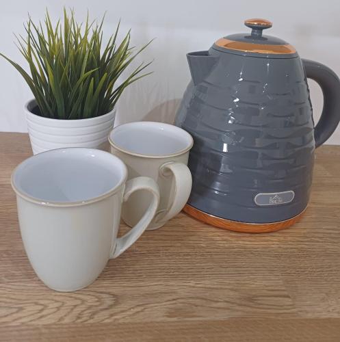 a coffee maker and two cups on a table at Tollymore Lodge in Newcastle