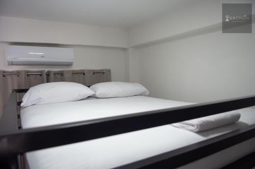 a bed with white sheets and pillows in a room at KRONOS APARTMENTS in Paramaribo