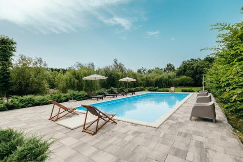 a swimming pool with chairs and umbrellas on a patio at Moslavačka Priča Holiday Homes in Mala Ludina