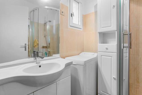 une salle de bain blanche avec un lavabo et une douche dans l'établissement Joli 43m2 , Vue mer , piscine , parking, à Saint-Raphaël