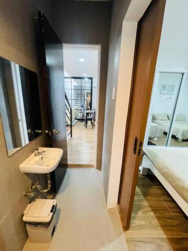 a bathroom with a sink and a toilet and a bed at Homestay CDO - Ventura in Cagayan de Oro