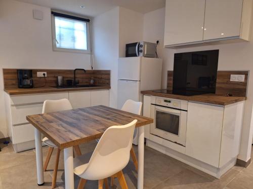 - une cuisine avec une table en bois et des chaises blanches dans l'établissement Maisonnette en Provence, à Figanières