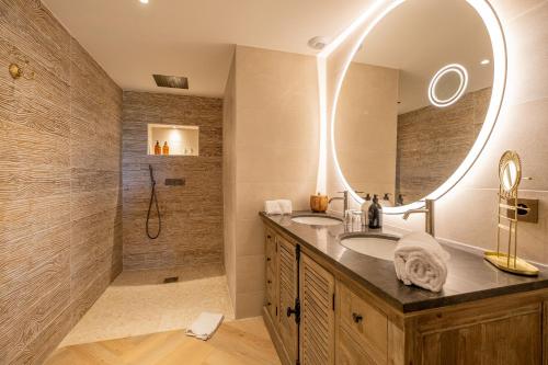 a bathroom with a sink and a shower with a mirror at L'Orée du Bois - Hôtel & Spa in Montagudet