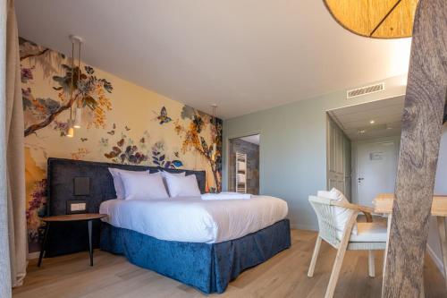 a bedroom with a bed and a table and a chair at L'Orée du Bois - Hôtel & Spa in Montagudet