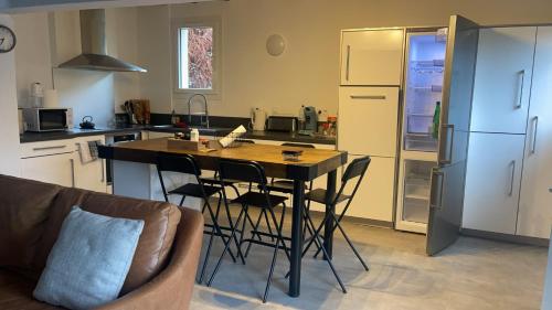une cuisine avec une table, des chaises et un réfrigérateur dans l'établissement Maison la Bouscasse, à Gabriac