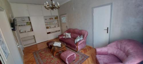 a living room with two pink chairs and a table at Downtown Veliko Tarnovo 2 in Veliko Tŭrnovo