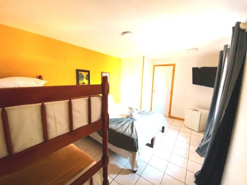 a bedroom with a bed and a yellow wall at Pousada Turquesa By Gente Bonita in Búzios