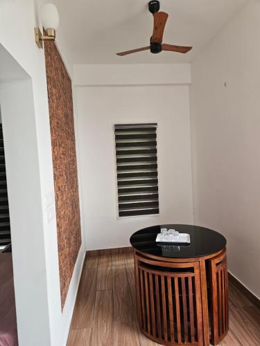 a room with a table and a ceiling fan at Yogis Inn in Kozhikode