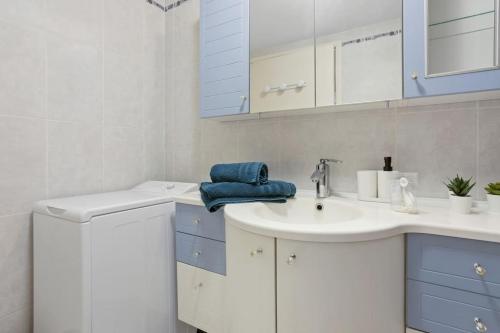 La salle de bains est pourvue d'un lavabo blanc et de placards bleus. dans l'établissement Joli 65m2 piscine parking, à Saint-Raphaël